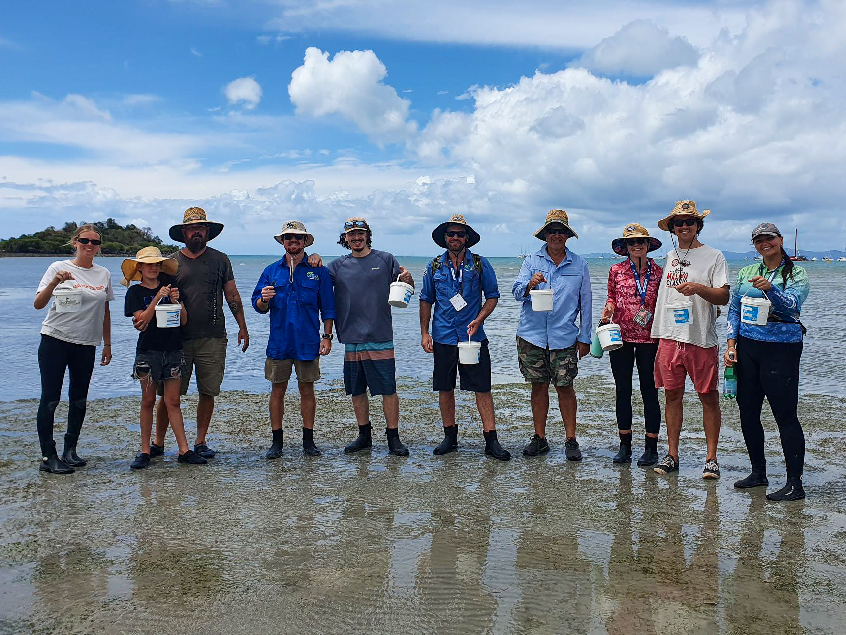 Volunteers with buckets collecting seagrass flowers at low tide on a beach