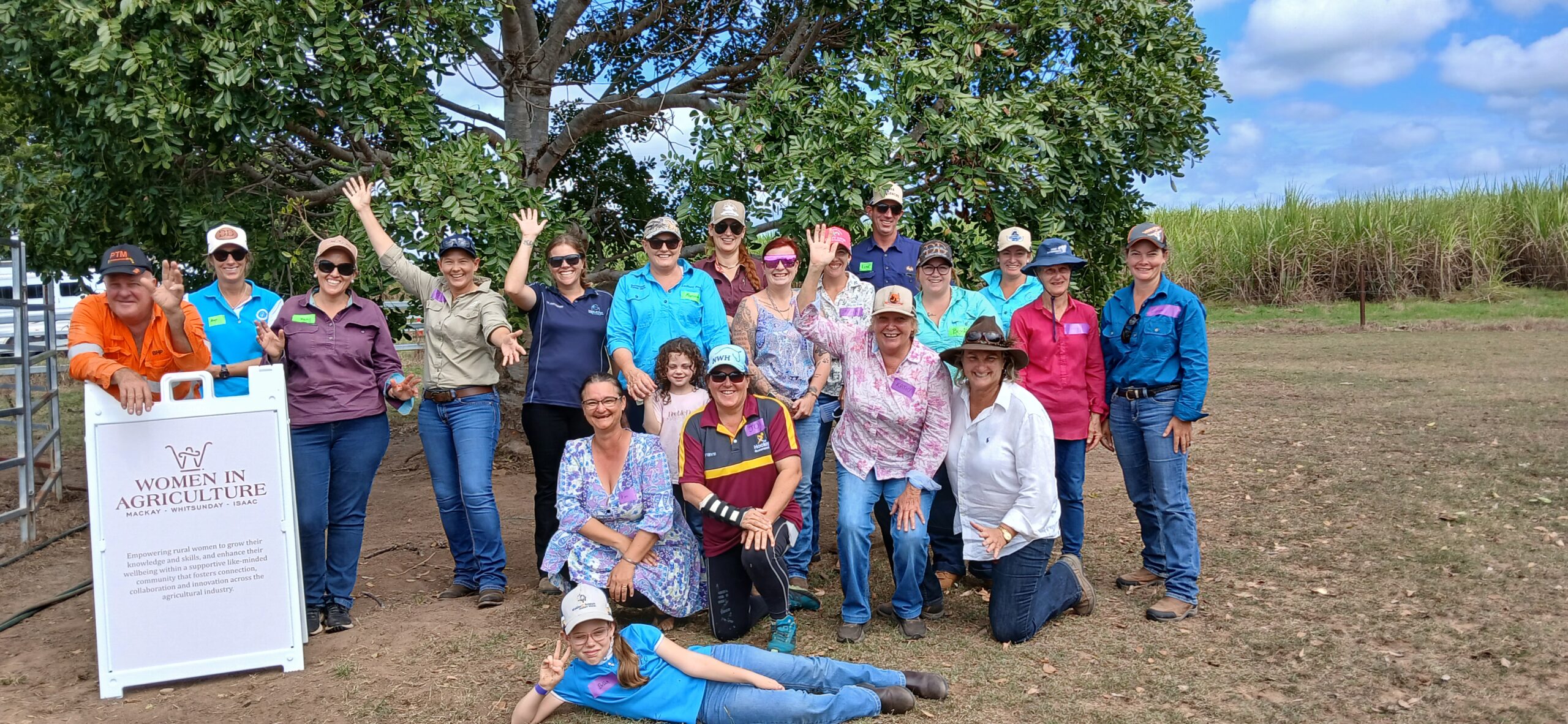 group photo of women with women in agriculture sign in front of cane field.