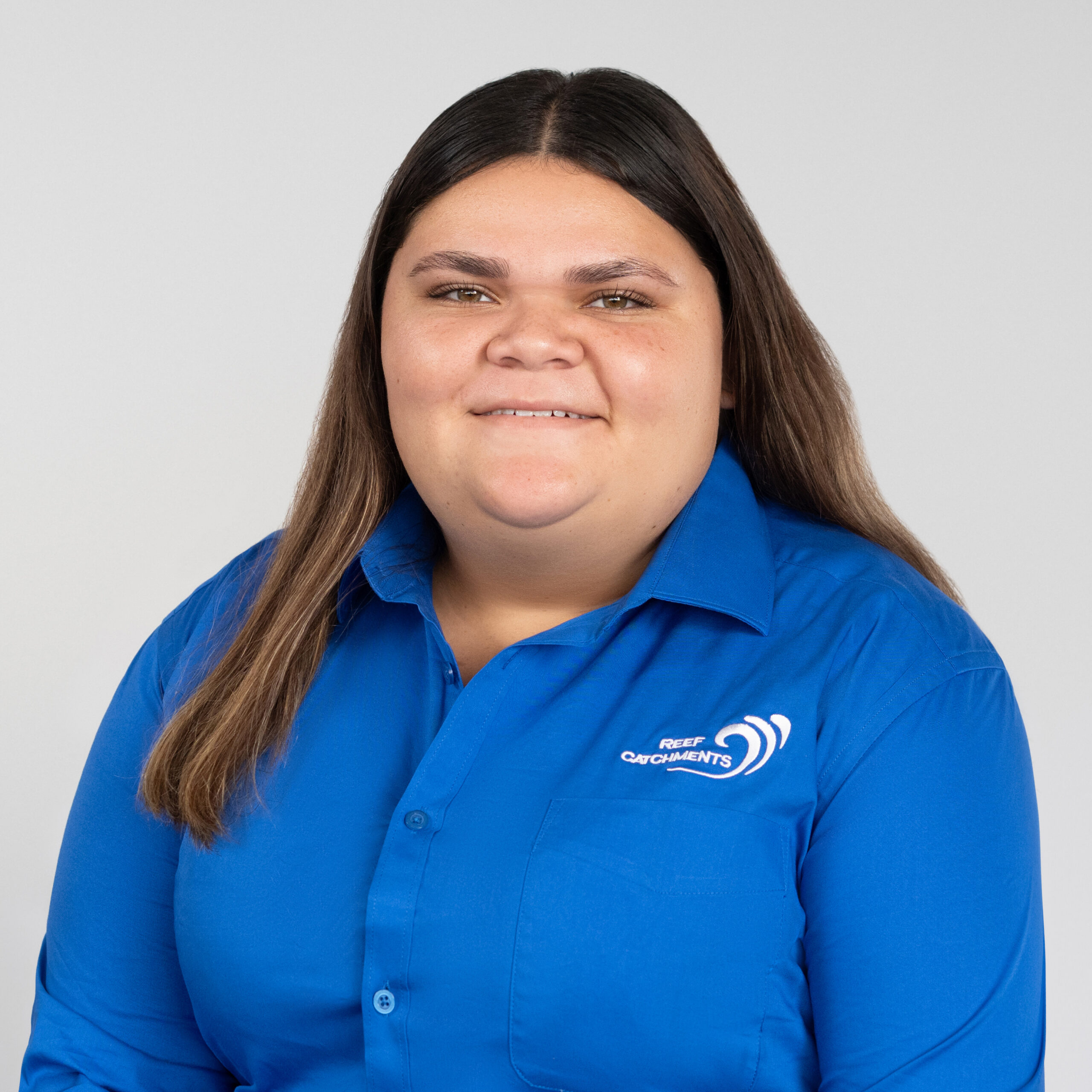 Headshot of Gabi Antrm in a blue shirt with white embroided Reef Catchments logo against a neutral background.